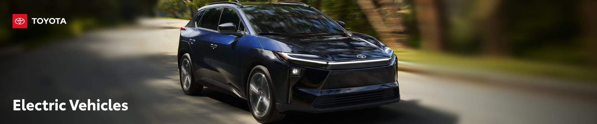 Dark blue electric SUV driving on a tree-lined road.