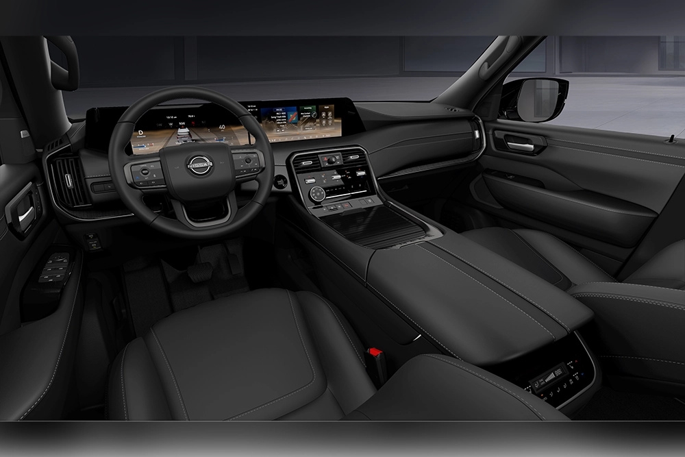 2027 Nissan Armada Dark Armor black cockpit with steering wheel, dashboard displays and center console.