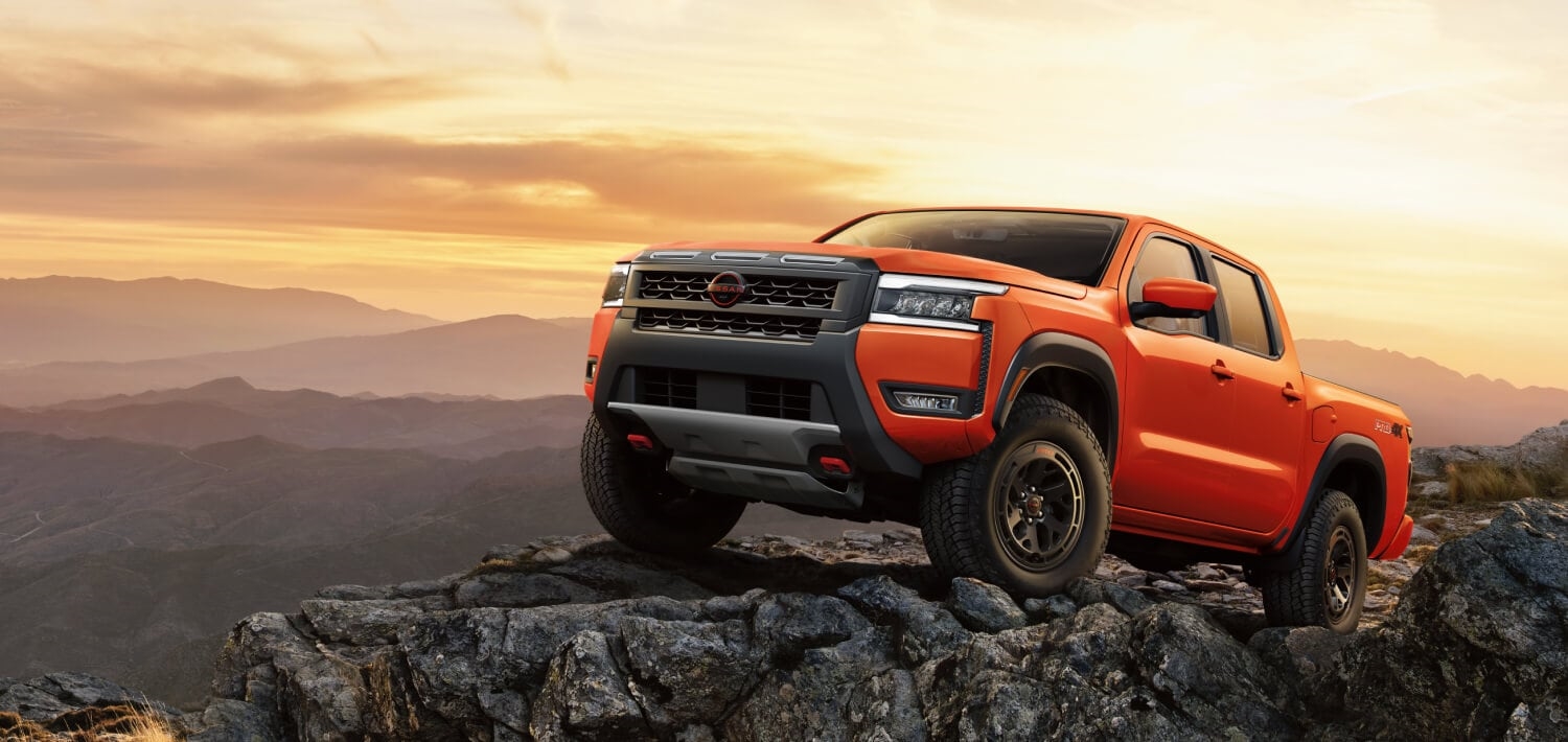 2026 Nissan Frontier in red, parked on a rugged peak with a twilight sky in the background