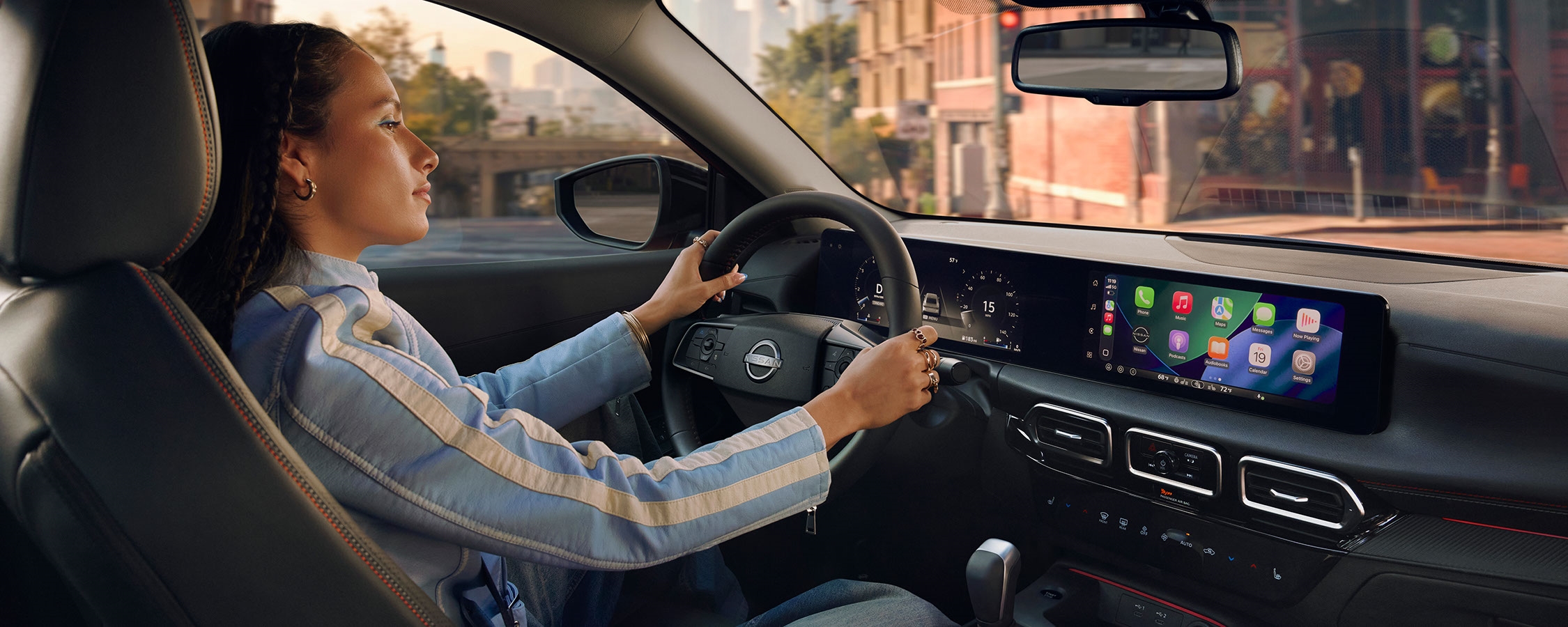 2026 Nissan Sentra cockpit with a driver at the steering wheel, digital displays and center console.