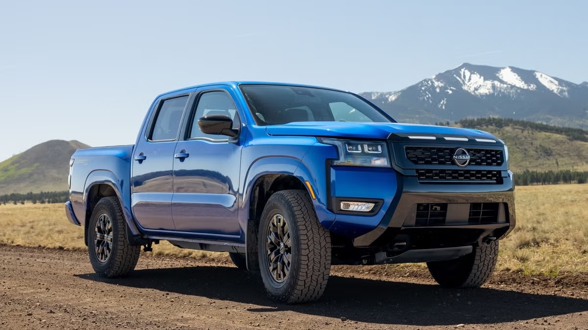 2027 Nissan Frontier Sport Edition in a front-right three-quarter view on a dirt road with mountains behind