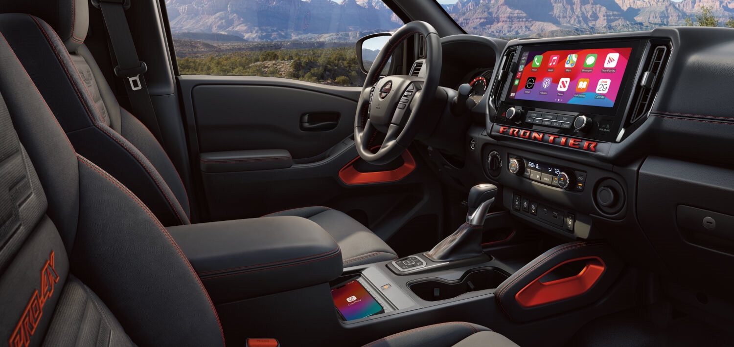 2027 Nissan Frontier PRO-4X cabin with Lava Red accents, touchscreen display and center console.
