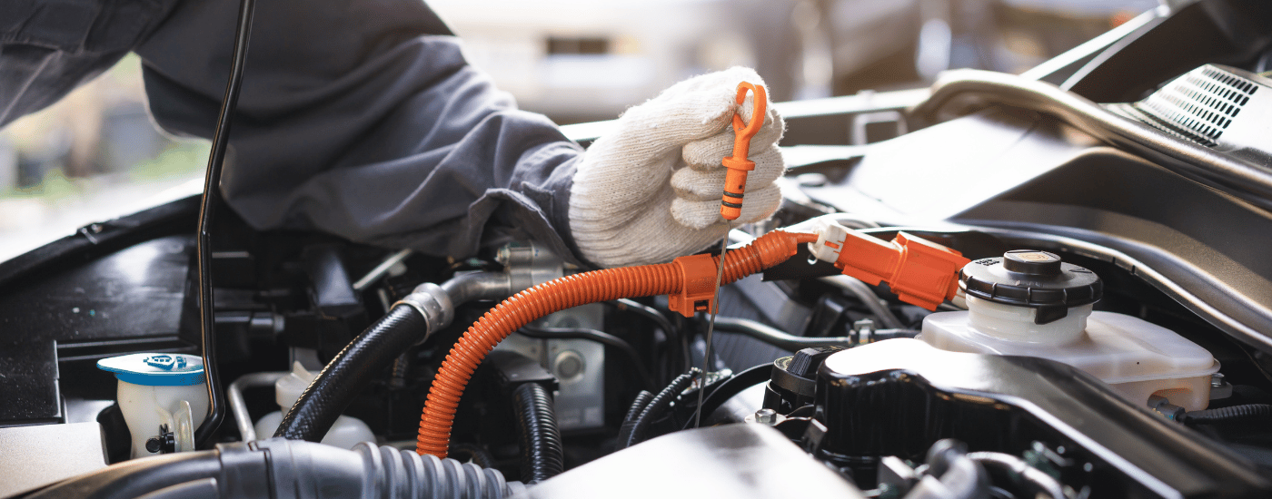 A mechanic checking the oil dipstick in a car