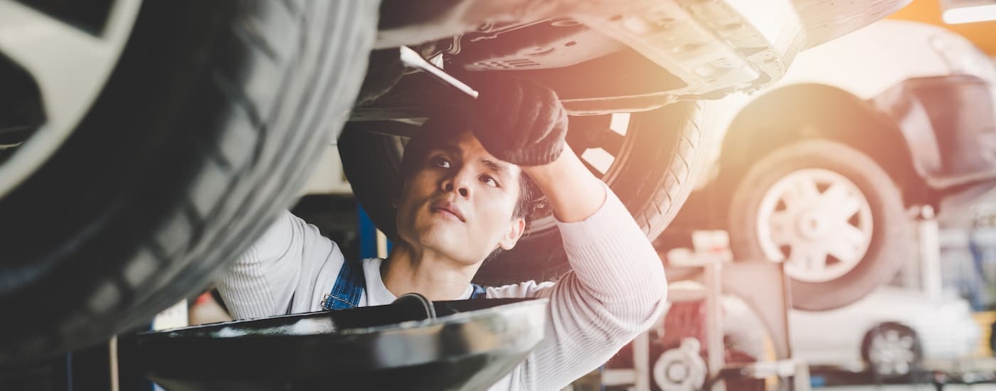 A service technician working on the underside of a car.