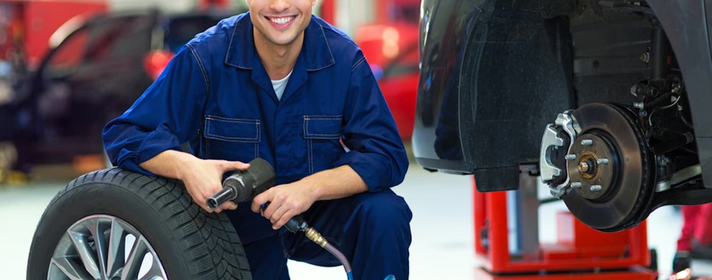 A service technician getting ready to install a tire on a vehicle.