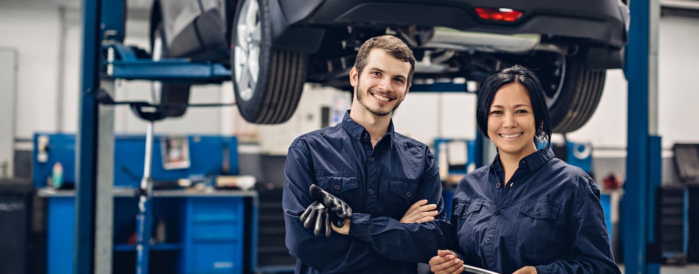 Two service technicians standing in front of a vehicle.