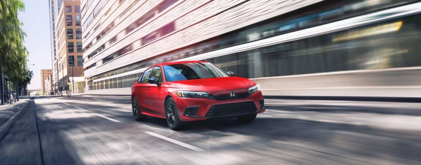 Red 2023 Honda Civic driving through a city