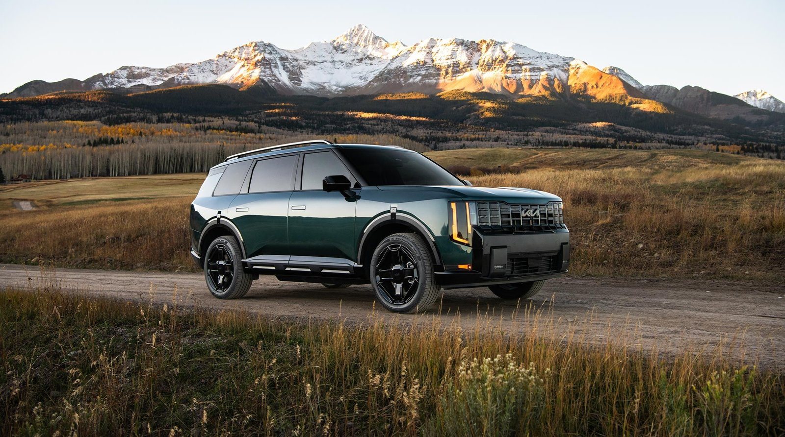 2027 Kia Telluride Hybrid in green on a gravel road below Colorado peaks