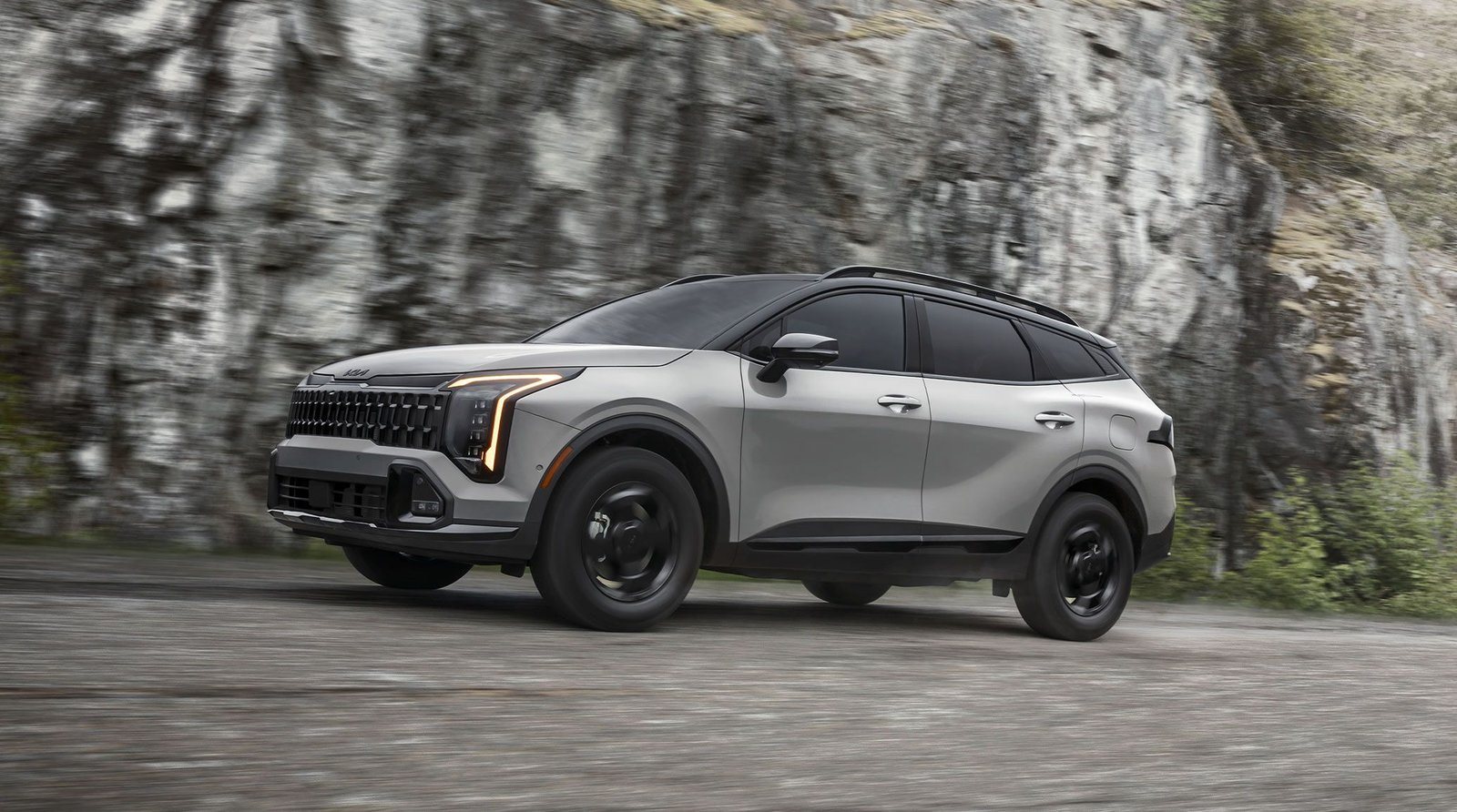 2027 Kia Sportage X-Pro Prestige driving past a rocky cliff
