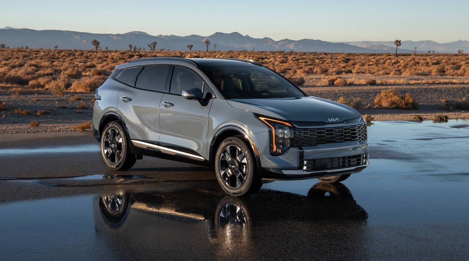 2027 Kia Sportage Hybrid in blue parked on wet pavement in the desert