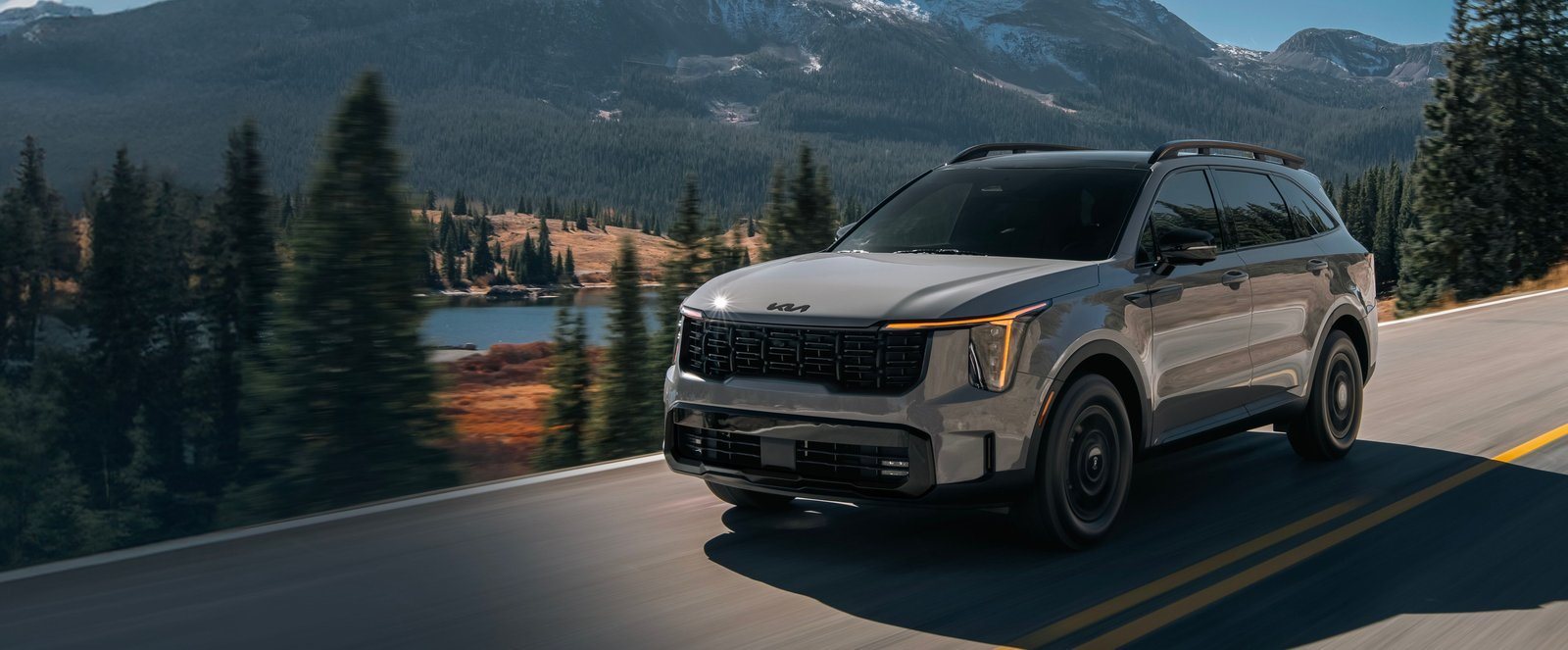 2027 Kia Sorento in gray driving on a mountain lake road