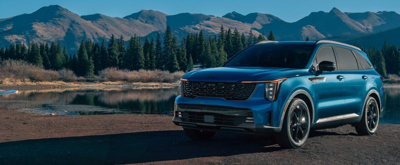 2027 Kia Sorento Hybrid in blue parked beside an alpine lake