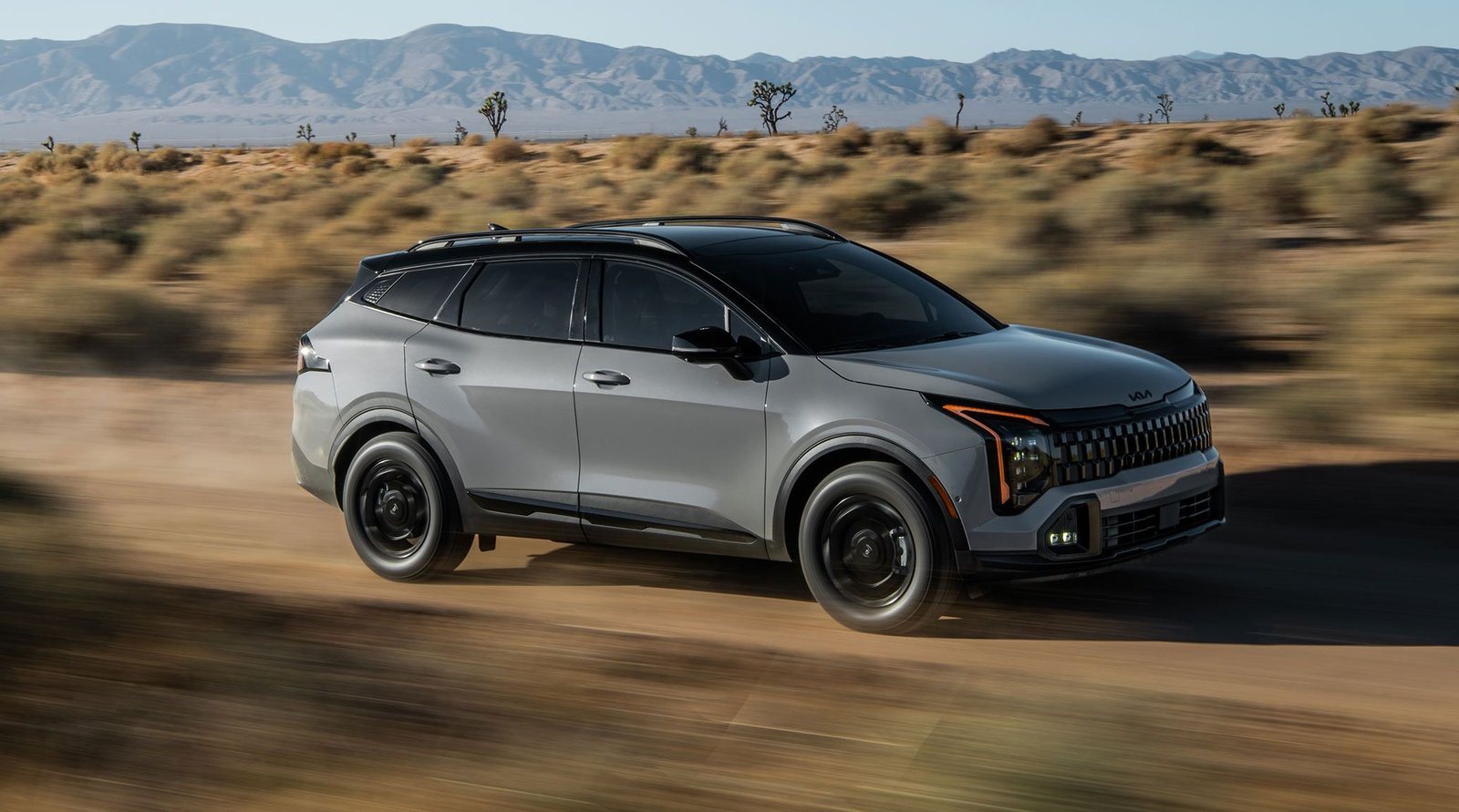 2027 Kia Sportage in silver driving through the desert