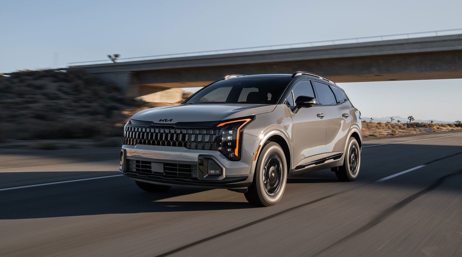 2027 Kia Sportage X-Pro in gray driving under a highway overpass