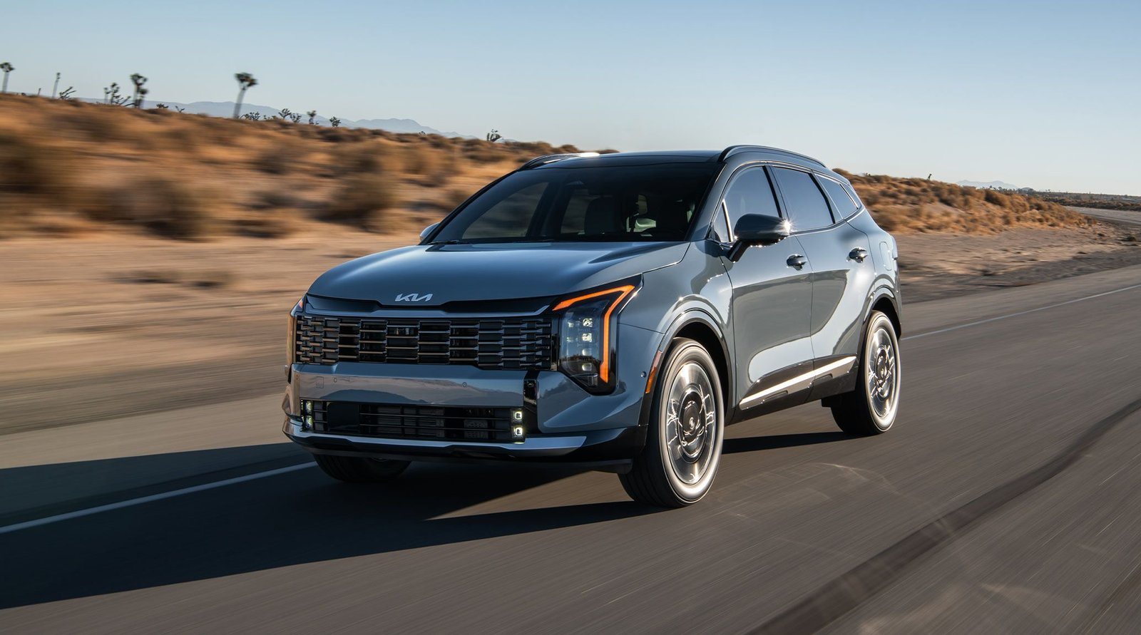 2027 Kia Sportage Hybrid in blue driving on a desert highway