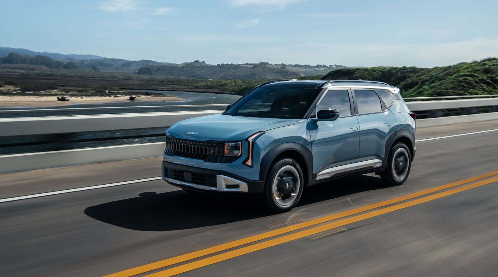 2027 Kia Seltos in light blue driving on a coastal highway