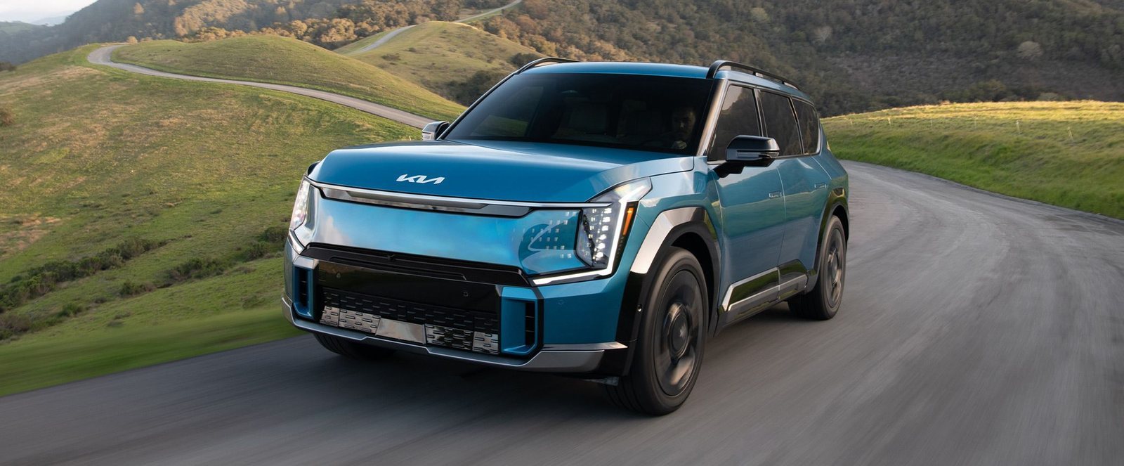 2026 Kia EV9 in blue driving on a hillside road