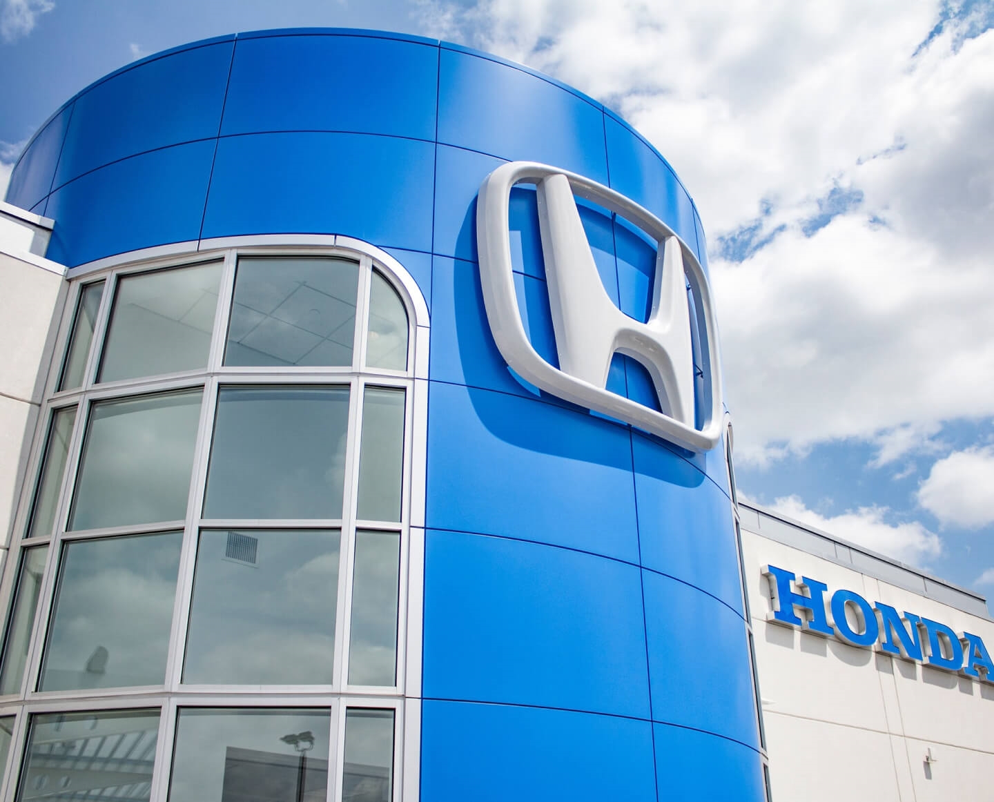 Low angle close-up shot of a Honda dealership sign against a partly cloudy sky.
