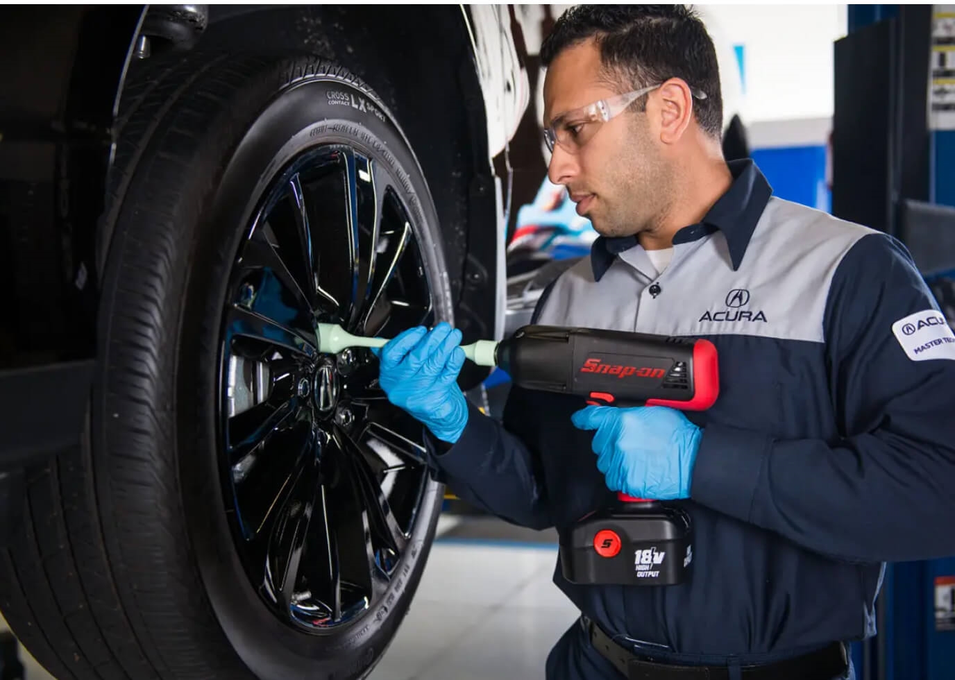 An Acura Certified Technician attached a wheel to an Acura vehicle with an impact wrench.