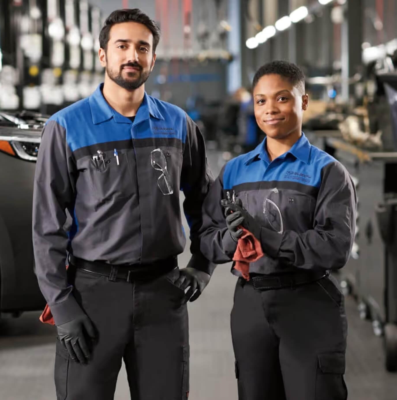 Two Subaru Service Technicians stand side-by-side in a Subaru service center.