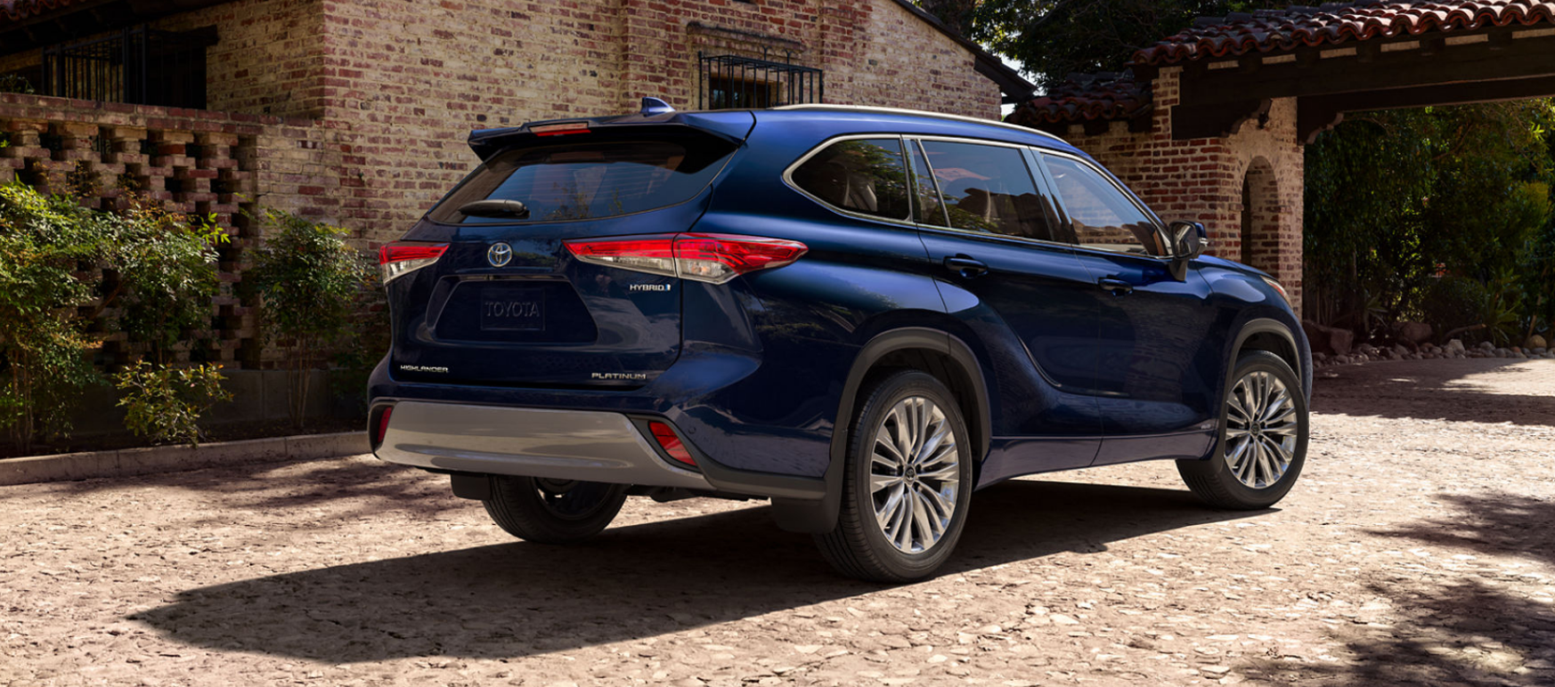 Rear view of a New Toyota Highlander Hybrid Platinum Blue parked on rocky road