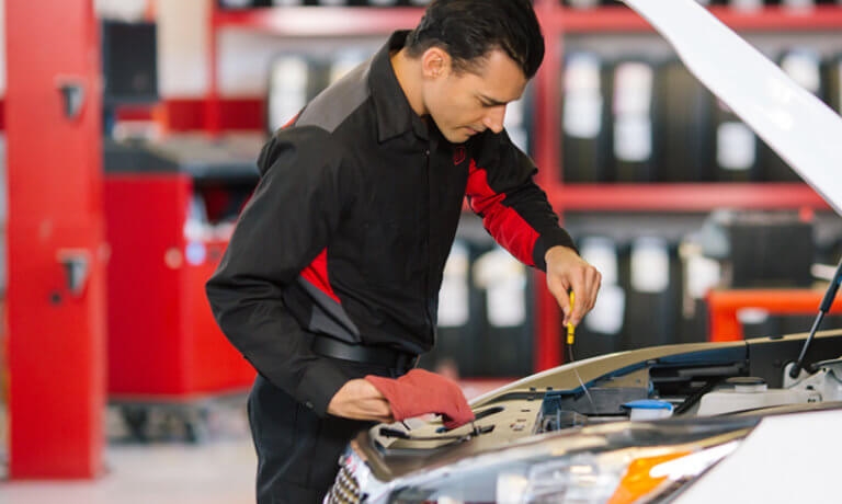 Kia service technician inspecting under hood