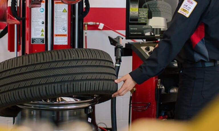 Kia service technician working on a tire